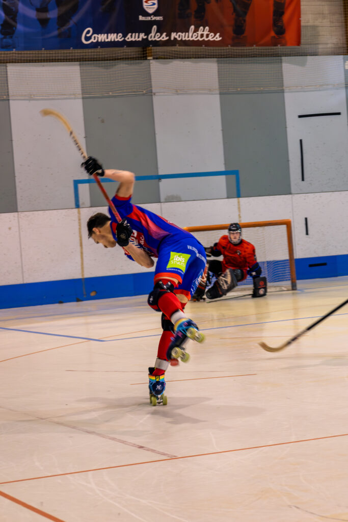 Joueur de rink hockey du SAM Hockey en action, prêt à tirer avec la crosse levée.
