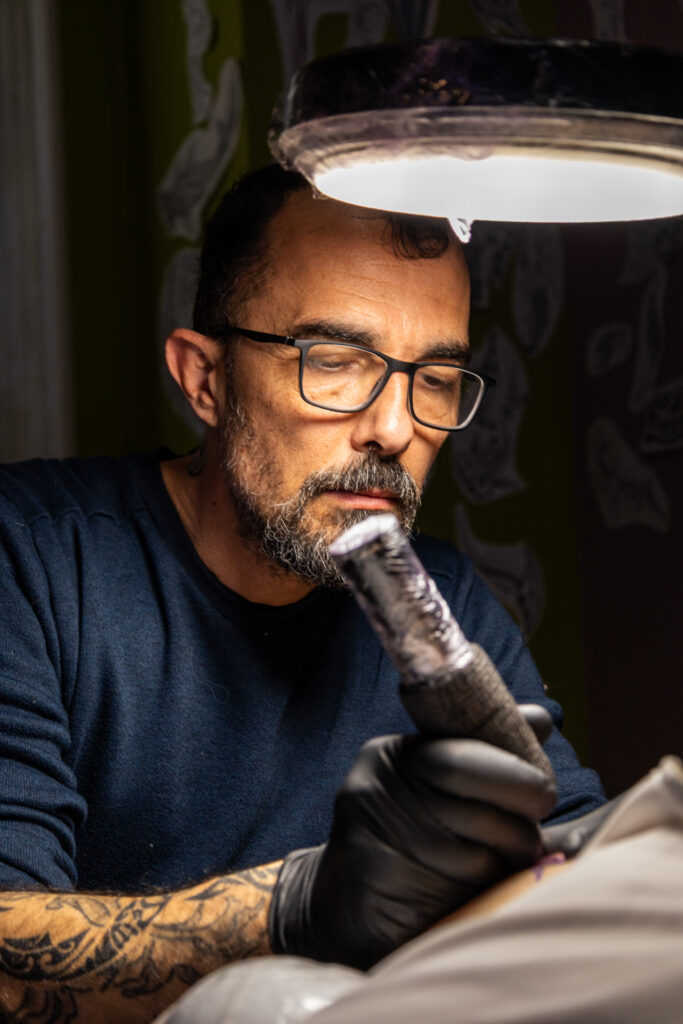 Tatoueur concentré avec son équipement en main.